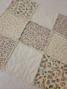 a patchwork quilt is laying on top of a white bed sheet with birds and flowers