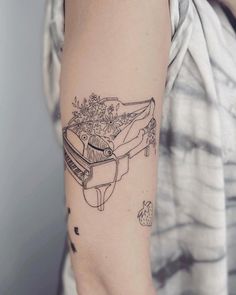 a woman's arm with a tattoo on it that has a piano and flowers