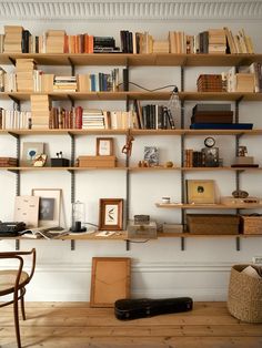 a bookshelf filled with lots of books next to a wooden chair and table