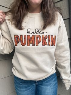 a woman wearing a white sweatshirt with the words hello pumpkin printed on it and smiling