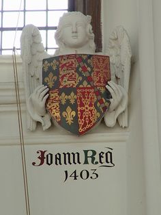 a coat of arms and shield on the side of a building with windows in the background