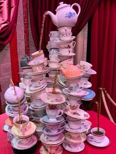 a table topped with lots of cups and saucers on top of a red cloth