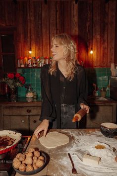 a woman standing in front of a table with dough and pastries on top of it