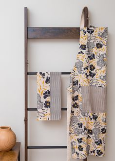 two towels hanging on a towel rack next to a vase and wooden chair with white walls