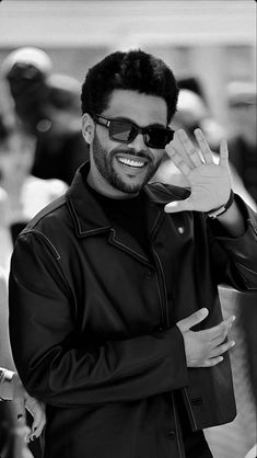 a man in sunglasses waves to the crowd