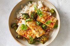 a bowl filled with rice and broccoli covered in sauce