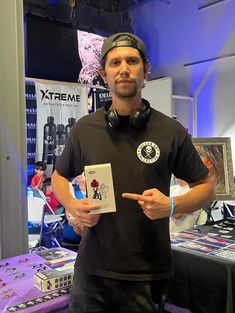 a man standing in front of a table with headphones on and holding a card