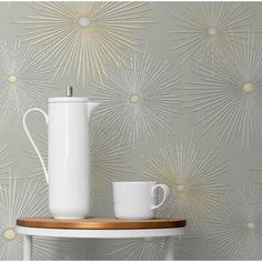 a white coffee pot sitting on top of a table next to a cup and saucer