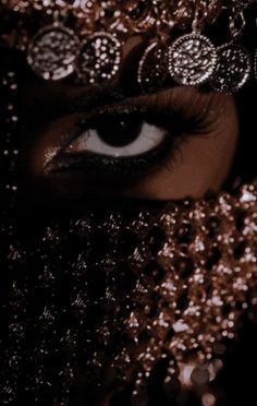 a woman's face is covered in gold and silver sequins, with her eyes wide open