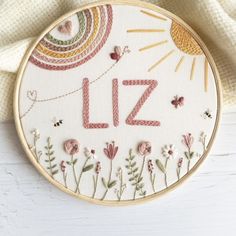 a cross stitch pattern with the word liz on it and flowers in front of a white background