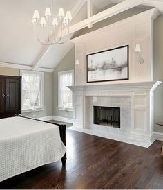 a large bedroom with a fireplace and white furniture