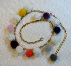 a multi colored pom - pom necklace on a gold chain