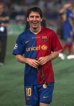 a soccer player smiles as he walks off the field with his medal around his neck