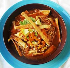 a blue bowl filled with taco soup and tortilla wedges on top