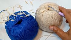 two balls of yarn being worked on by someone using a crochet hook and knitting needles