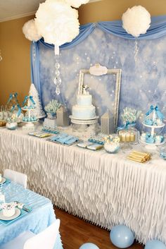 a table topped with blue and white desserts next to an ice princess wallpaper