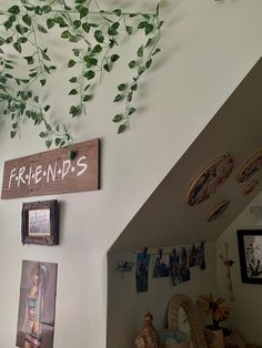 there is a sign that says friends hanging on the wall next to pictures and plants