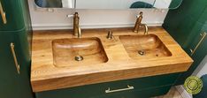 two wooden sinks sit in front of a mirror on a wall next to green cabinets