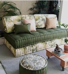 a living room filled with green furniture and lots of pillows on top of the couch