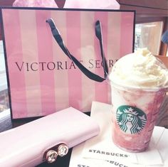 a starbucks drink with whipped cream in it next to a pink bag and other items