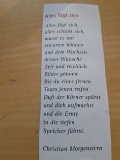 a close up of a piece of paper on a wooden table with words written in german