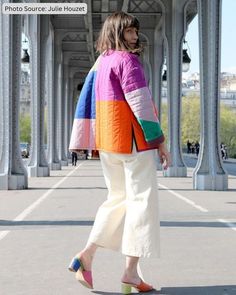 a woman walking down the street wearing colorful clothing