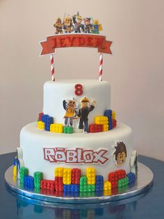 a birthday cake decorated with legos and characters on it's top tier is shown