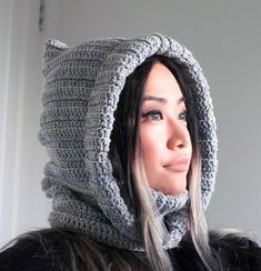 a woman wearing a gray crochet hat and scarf with a hood on her head