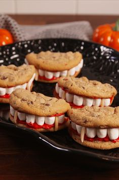 chocolate chip cookies with marshmallows and teeth are on a black platter