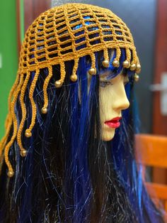 a mannequin head with blue hair and gold beads on it's head