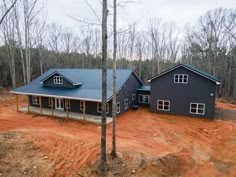 an aerial view of a house in the woods with dirt on the ground and trees around it