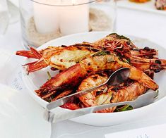 a white plate topped with shrimp next to a candle