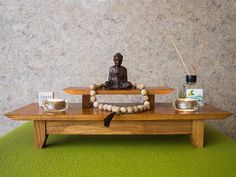 a buddha statue sitting on top of a wooden table next to candles and other items