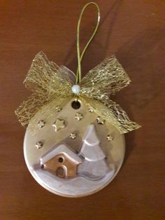 a christmas ornament hanging on a wooden table with gold ribbon and star decorations