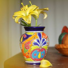 a colorful vase with yellow flowers in it