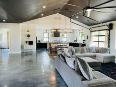 a large open living room and kitchen area with gray couches, white walls and black ceiling