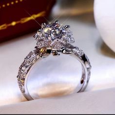 a close up of a diamond ring on a table with a box in the background