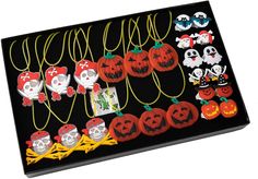 an assortment of halloween decorations are displayed on a black tray with yellow cords and tags