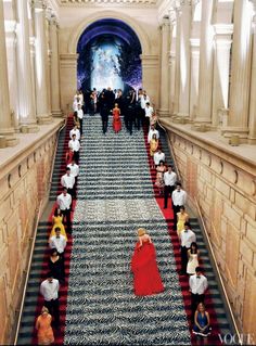 people are walking up and down the stairs in an ornate building with columns on either side