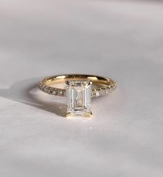 an emerald cut diamond ring with pave set shoulders