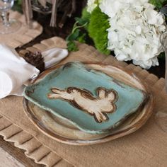 a close up of a plate on a table with napkins and flowers in the background