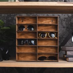 a wooden shelf with sunglasses on top of it next to a clock and some books