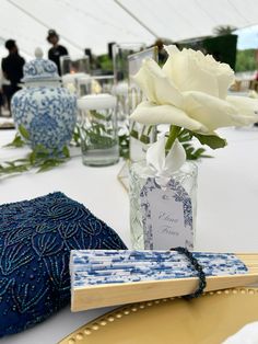 white roses in a vase sitting on a table with blue and white decorations around it