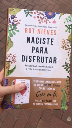 a person holding up a book with spanish writing in front of them on a brick sidewalk