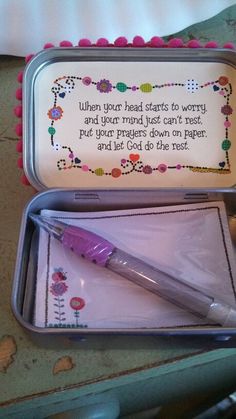 a pink pen sitting in a metal container on top of a table next to a notepad