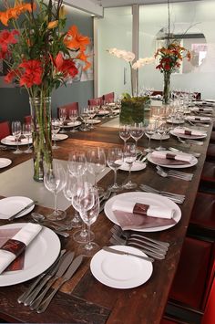 the table is set with place settings and flowers in vases on each side, along with empty wine glasses