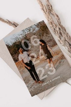 an image of two people standing next to each other in front of some dried grass