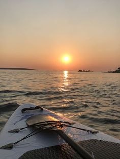 the sun is setting over the water from a kayak