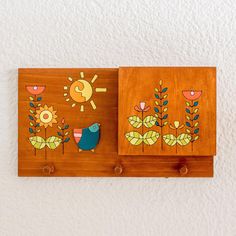 two wooden wall hangings with painted flowers and birds on them, one has a sun in the background