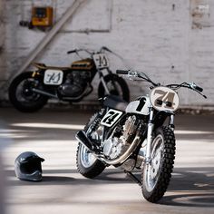 two motorcycles parked next to each other in a parking lot with a helmet on the ground